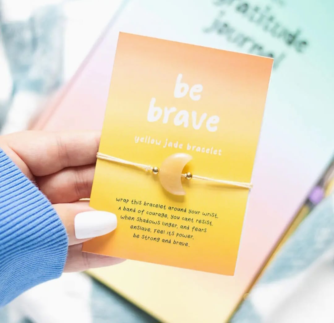 geel kaartje met daarop de gele jade armband in de vorm van een halve maan. 