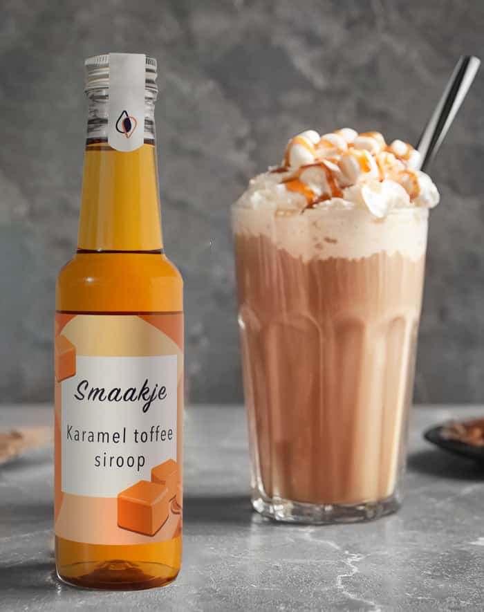 doorzichtige kunststof flesje met karamel toffee siroop naast een groot glas met koffie en slagroom