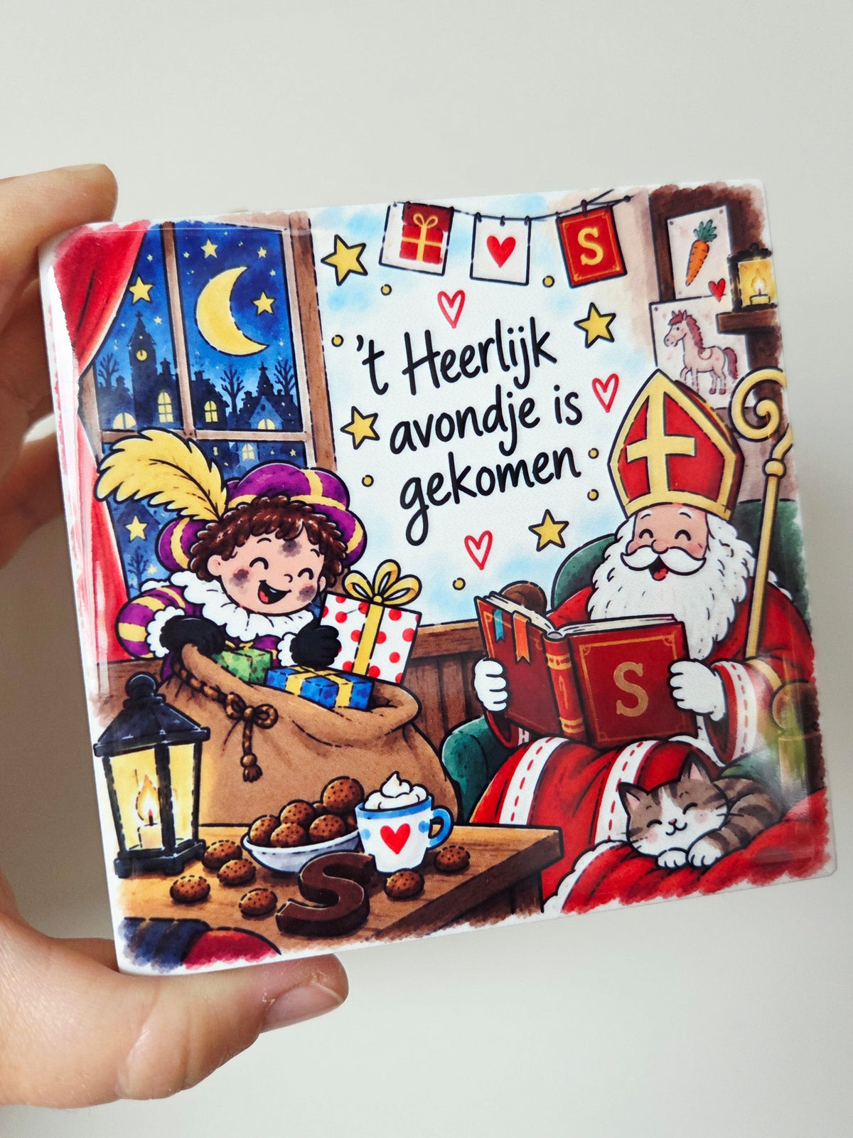 Sinterklaas Tegeltje - 't Heerlijk avondje is gekomen met een vrolijk pietje die een zak vasthoudt en een Sinterklaas met het grote boek
