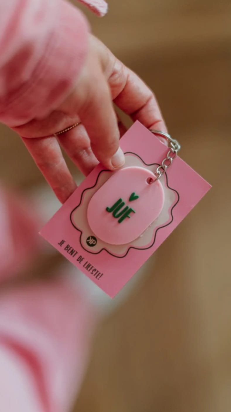 Roze sleutelhanger met de tekst Juf en een hartje geplaatst op een roze kaartje
