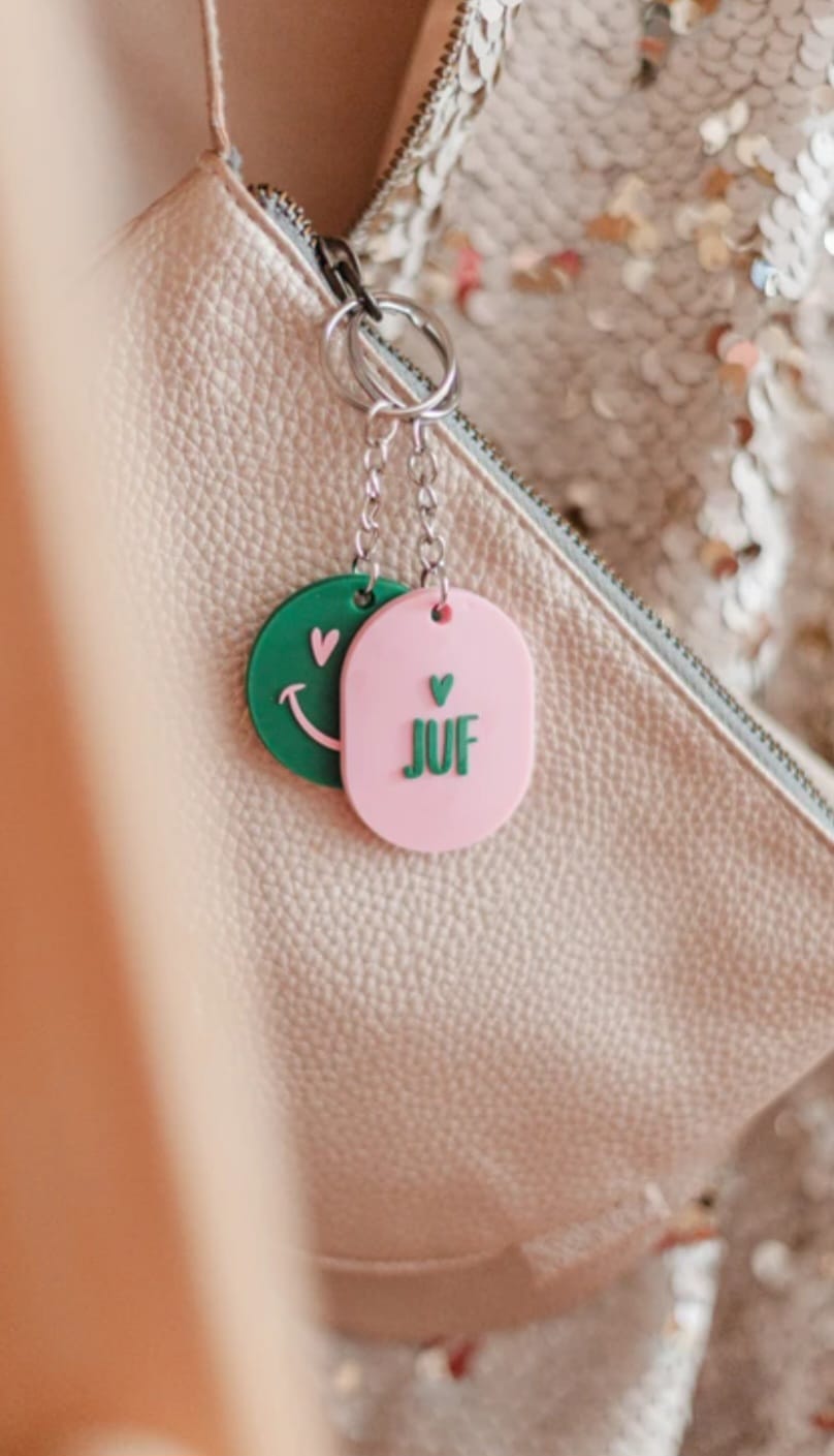 Roze sleutelhanger met de tekst Juf en een hartje geplaatst op een roze kaartje