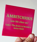Roze tegel met groene letters en de tekst Ambitchious. The desire to become a better bitch