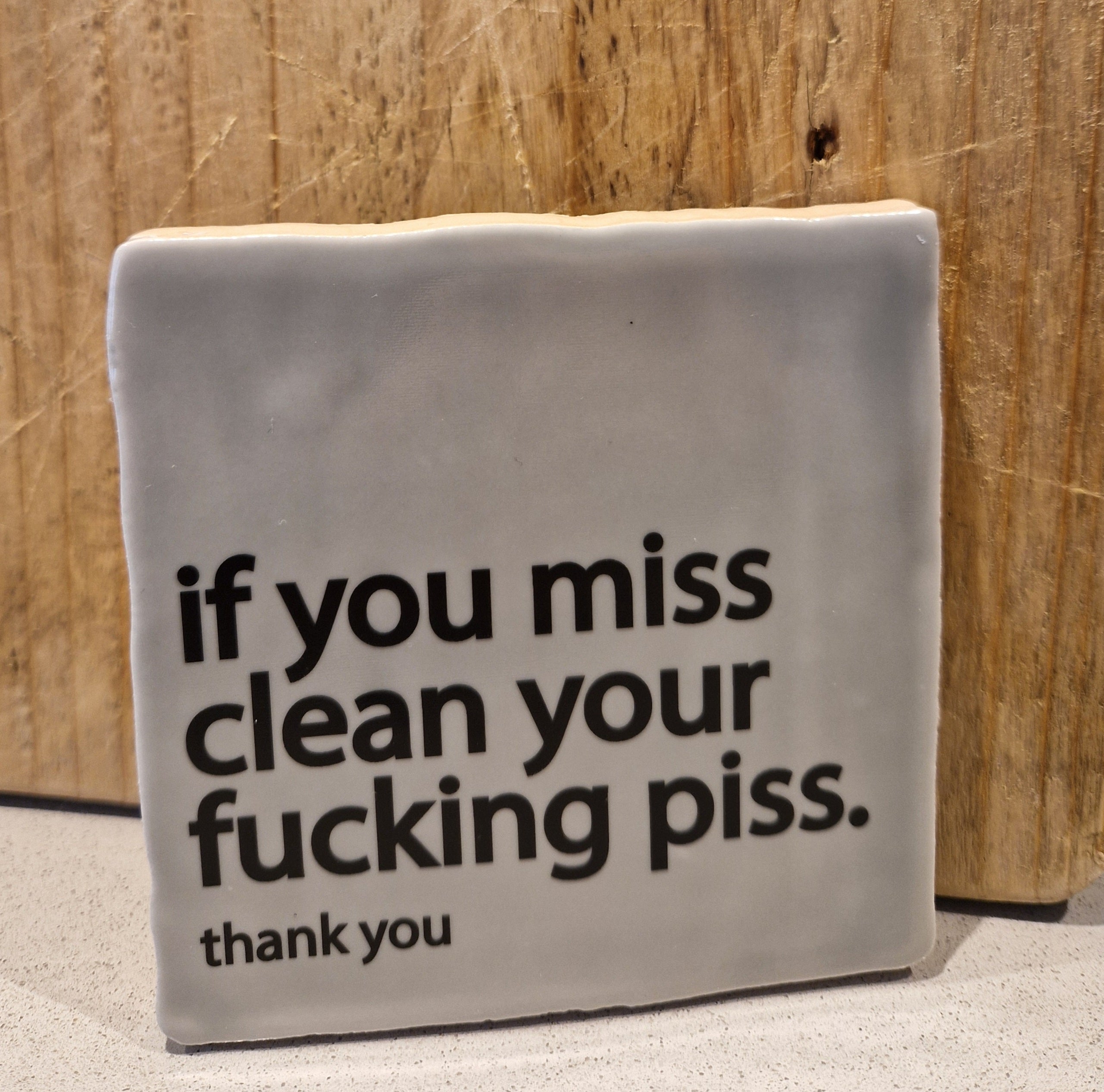 Saliegroen wc tegel met de tekst if you miss, clean your piss