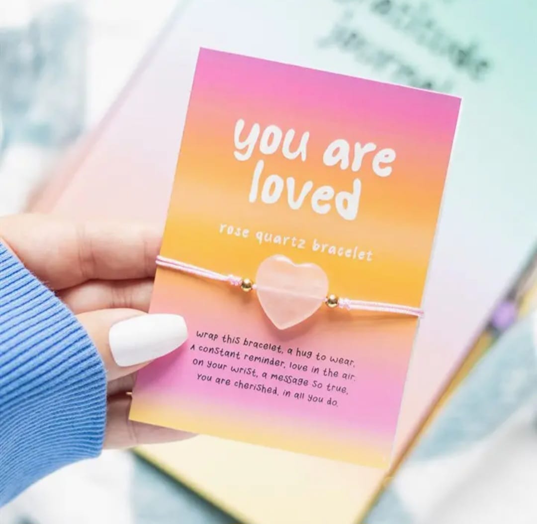 Roze en geel kaartje met daarop een rozenkwarts armbandje in de vorm van een hartje
