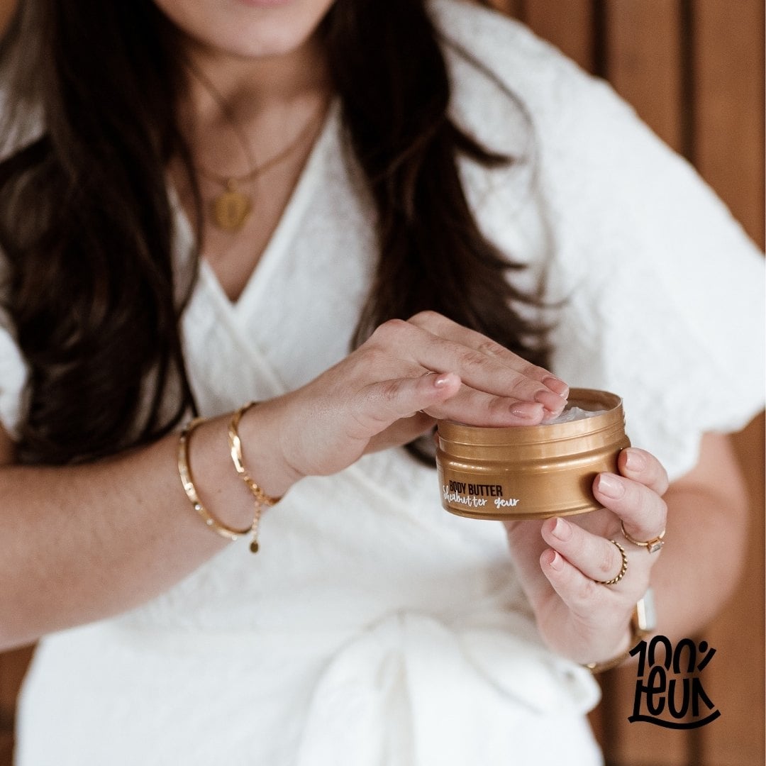 Pot geopende bodybutter in hand van dame