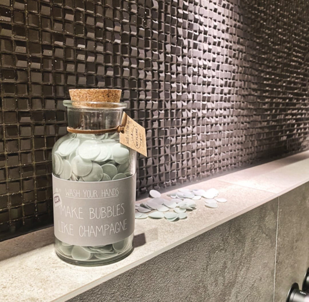 Een glazen fles met confetti handzeep en de tekst make bubbles like champagne